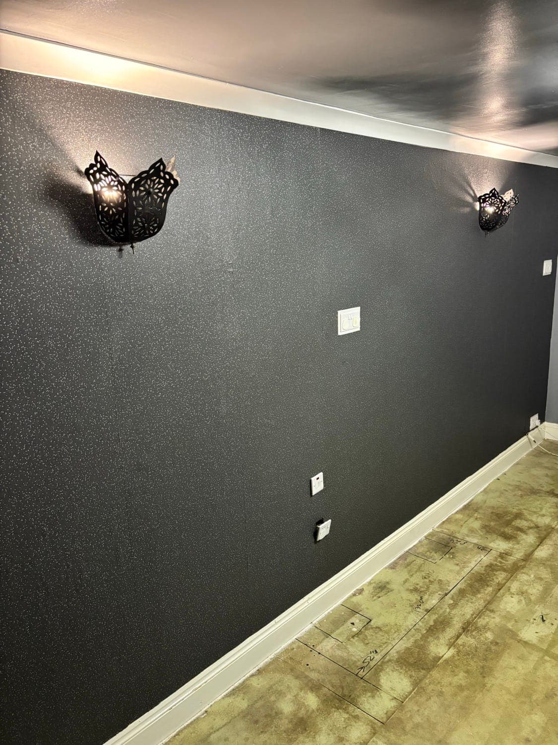 Living room walls painted charcoal grey with white ceiling and decorative black wall lights