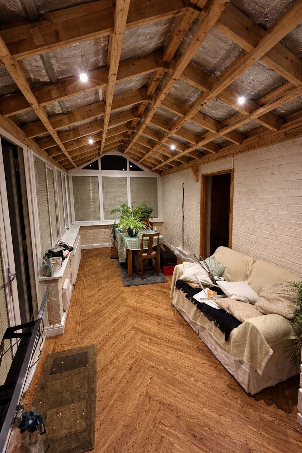 The same conservatory before the work, with the ceiling stripped back to the roof timbers